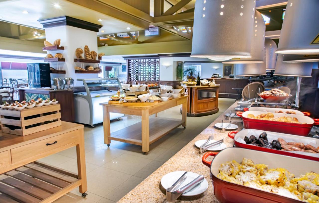 GHL Hotel Tequendama Bogotá Exterior foto The photo shows a dining area, likely in a buffet-style restaurant or hotel. There are several food stations with a variety of dishes displayed. 

- In the foreground, there are large, red serving dishes filled with different food items, including ri